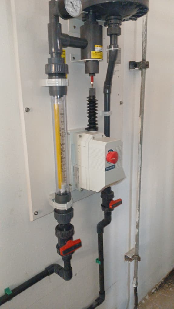 Side view of installed safety rinse station with valves, gauge, and piping